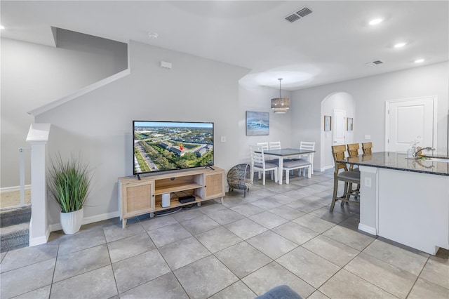 living area with arched walkways, light tile patterned flooring, visible vents, and recessed lighting