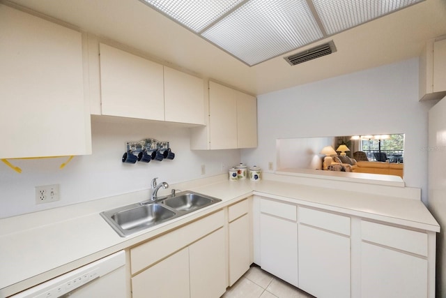 kitchen with light tile patterned floors, white dishwasher, sink, and white cabinets