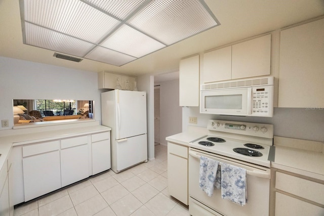 kitchen with white cabinets, light tile patterned floors, and white appliances