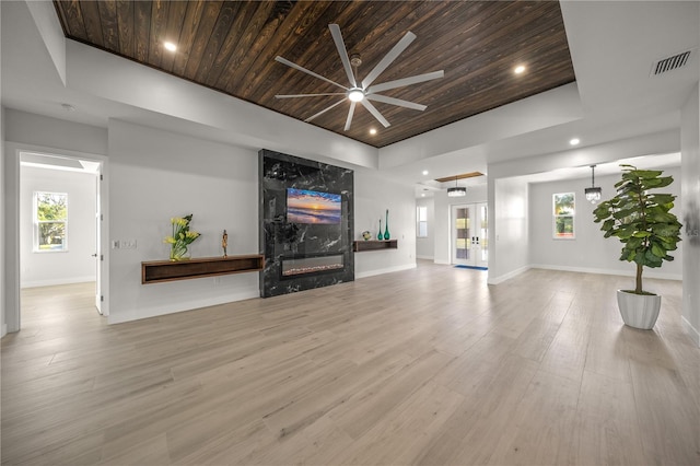 living room featuring light hardwood / wood-style floors, a raised ceiling, wood ceiling, and a fireplace