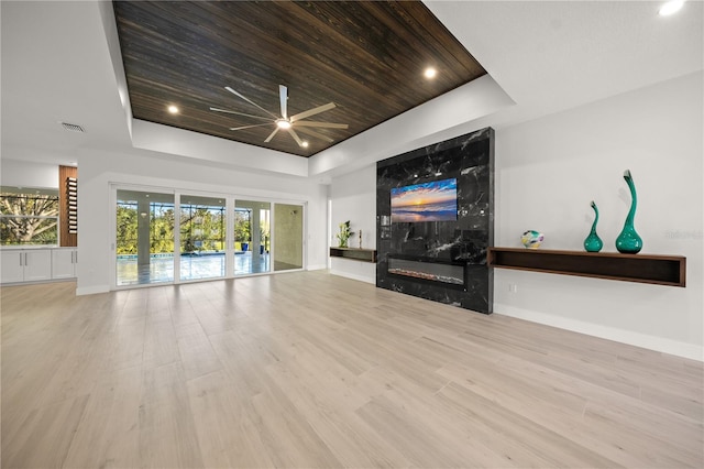 living room featuring a premium fireplace, a raised ceiling, wood ceiling, and light hardwood / wood-style flooring