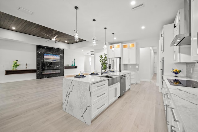 kitchen featuring tasteful backsplash, white cabinetry, light stone countertops, an island with sink, and stainless steel appliances