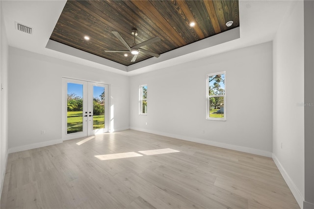 spare room with french doors, a raised ceiling, light hardwood / wood-style floors, and wood ceiling