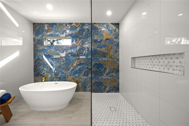 bathroom with tile walls and shower with separate bathtub