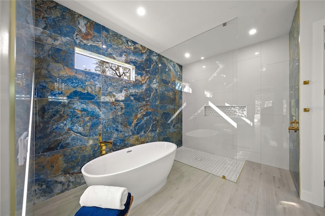 bathroom with hardwood / wood-style floors, separate shower and tub, and tile walls