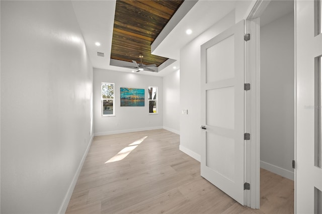 hallway with wooden ceiling, light wood-type flooring, and a raised ceiling