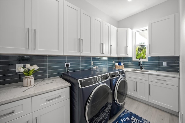 laundry room featuring sink, light hardwood / wood-style flooring, cabinets, and independent washer and dryer