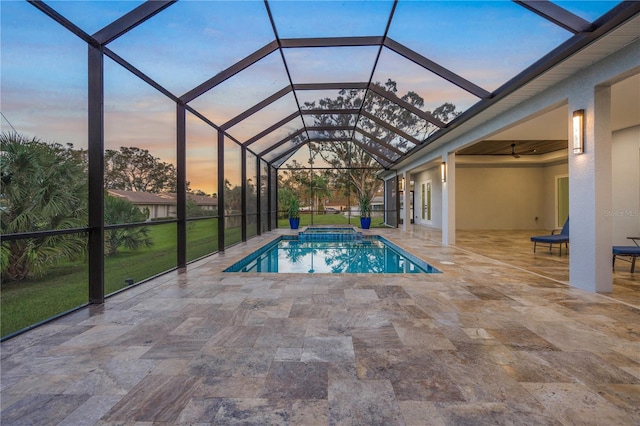 pool at dusk featuring glass enclosure and a patio