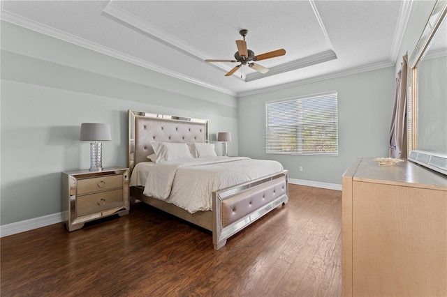 bedroom featuring crown molding, a textured ceiling, dark hardwood / wood-style flooring, a tray ceiling, and ceiling fan