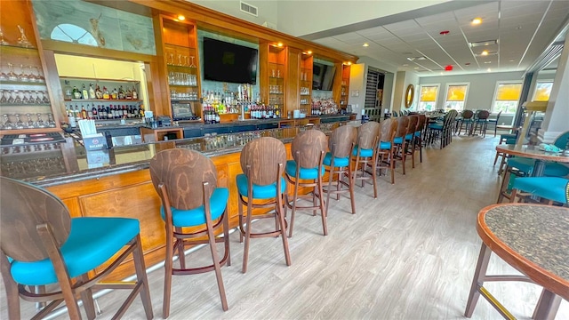 bar featuring a paneled ceiling and light hardwood / wood-style floors