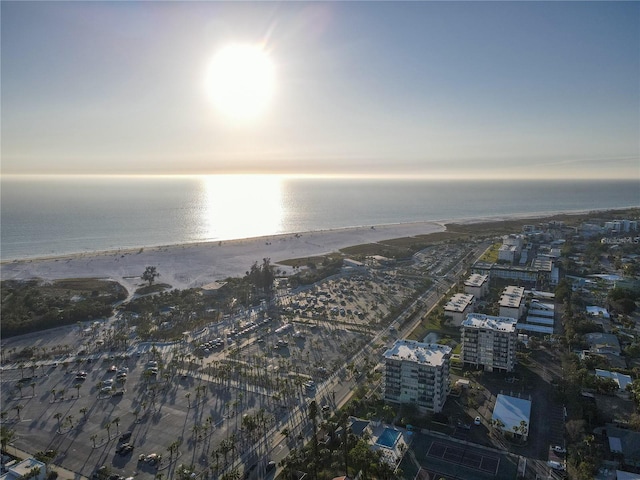 aerial view at dusk featuring a water view and a beach view