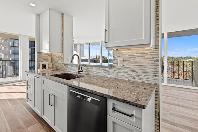 kitchen with light stone countertops, sink, white cabinetry, and dishwasher