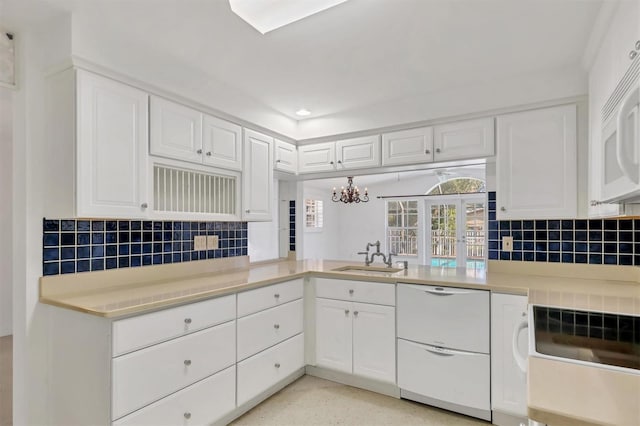 kitchen featuring a chandelier, sink, white cabinets, and backsplash