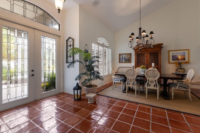 foyer with french doors, high vaulted ceiling, a chandelier, and dark tile patterned flooring