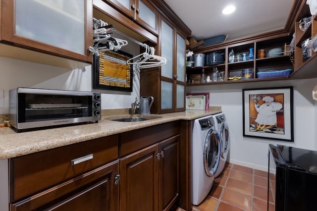 laundry room with tile patterned flooring, washer and dryer, and sink