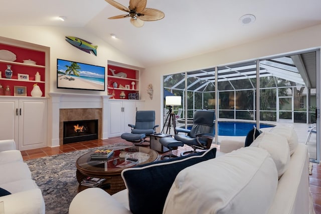 tiled living room featuring built in shelves, ceiling fan, a fireplace, and lofted ceiling