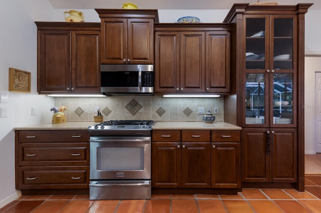 kitchen with stainless steel appliances, tile patterned floors, baseboards, and tasteful backsplash
