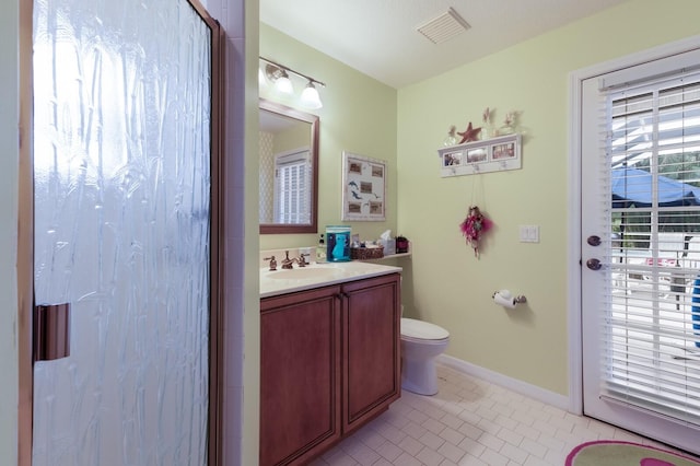 bathroom with a shower with shower door, vanity, toilet, baseboards, and visible vents