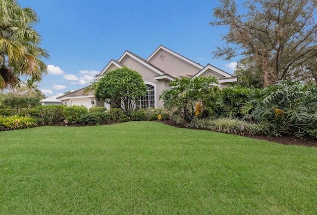 view of front of house featuring a garage, stucco siding, and a front lawn