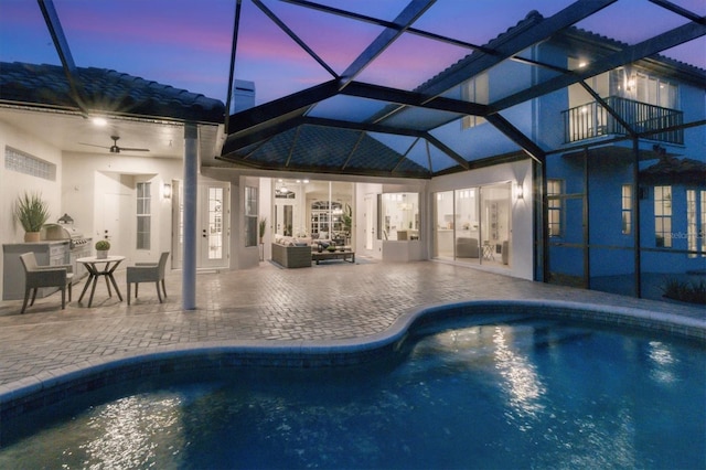 pool at dusk featuring french doors, ceiling fan, a patio, and a lanai