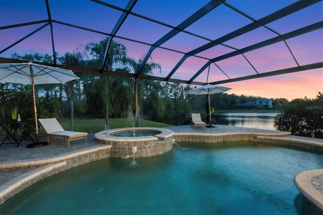 pool at dusk featuring a patio, a lanai, an in ground hot tub, and a water view