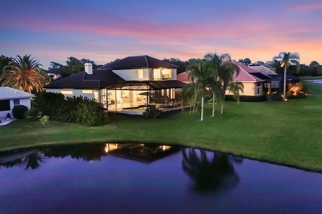 back house at dusk featuring a patio area, a gazebo, a yard, and a water view