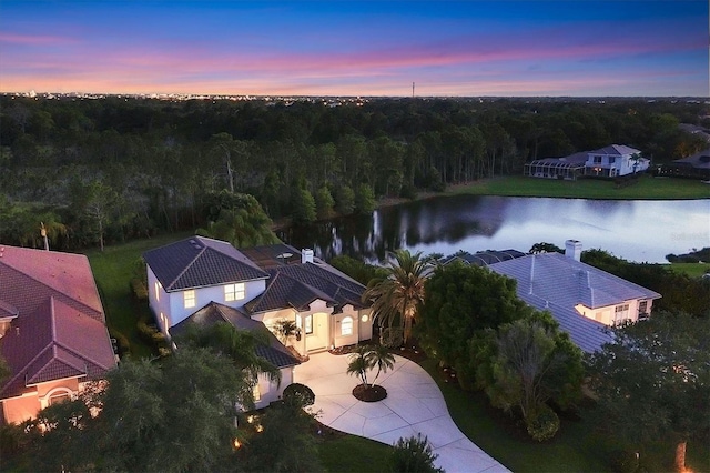 aerial view at dusk featuring a water view