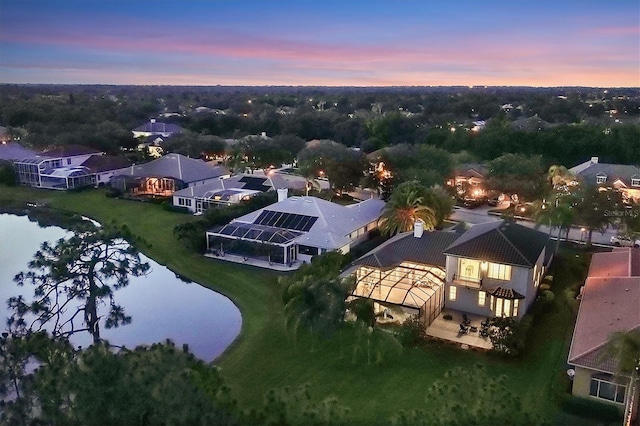 aerial view at dusk featuring a water view