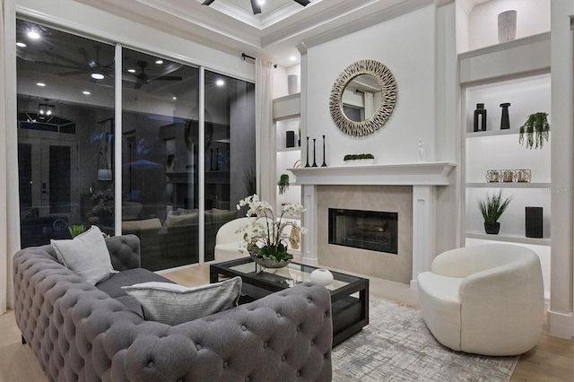 living room featuring a high end fireplace, hardwood / wood-style floors, built in shelves, and crown molding