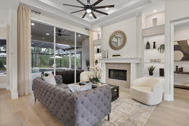 living room with crown molding, light hardwood / wood-style flooring, and a tray ceiling