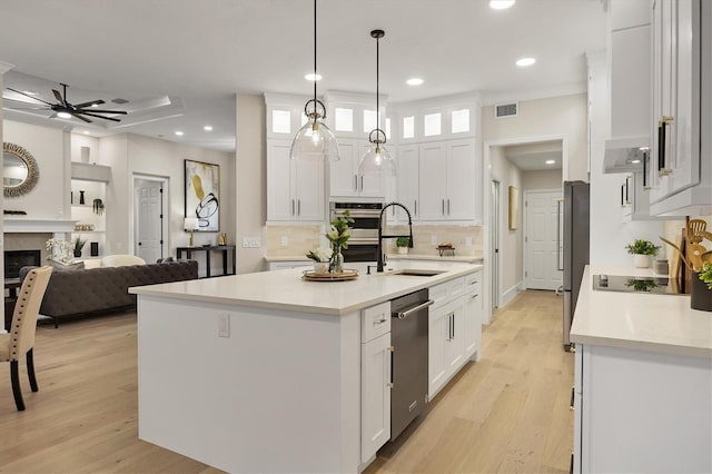 kitchen with stainless steel appliances, sink, pendant lighting, white cabinetry, and light hardwood / wood-style floors