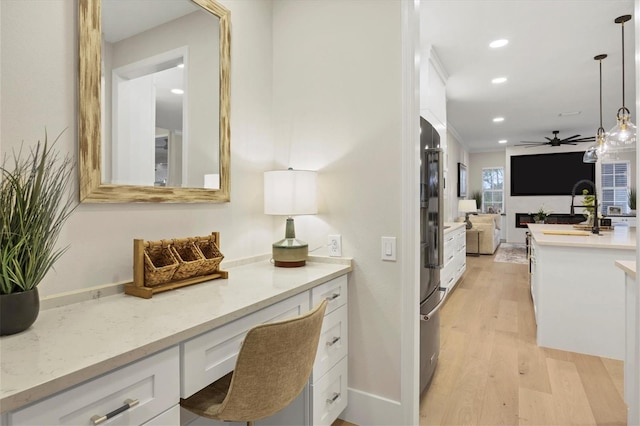 hall with ornamental molding, sink, and light wood-type flooring