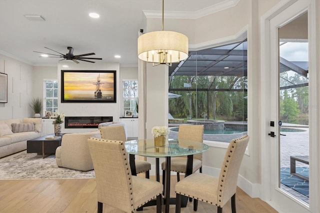 dining space with light hardwood / wood-style floors, crown molding, and a healthy amount of sunlight