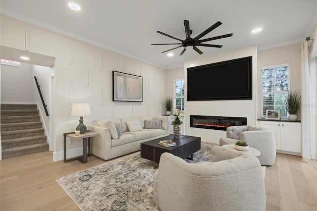 living room featuring light hardwood / wood-style floors, crown molding, and ceiling fan