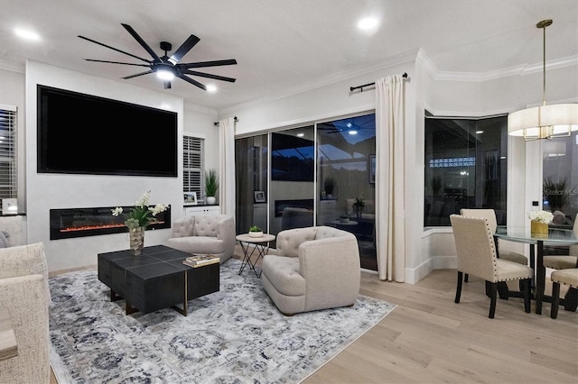 living room with ornamental molding, wood-type flooring, and ceiling fan