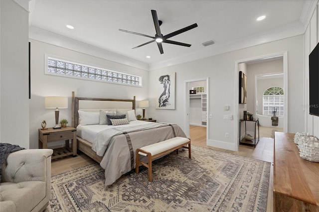 bedroom featuring a walk in closet, a closet, ceiling fan, light hardwood / wood-style floors, and crown molding