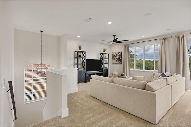 living room with light colored carpet and ceiling fan with notable chandelier