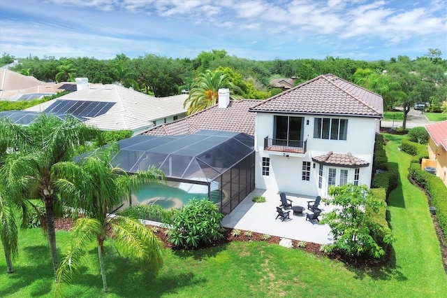 back of house featuring a lawn, a balcony, a patio, and glass enclosure