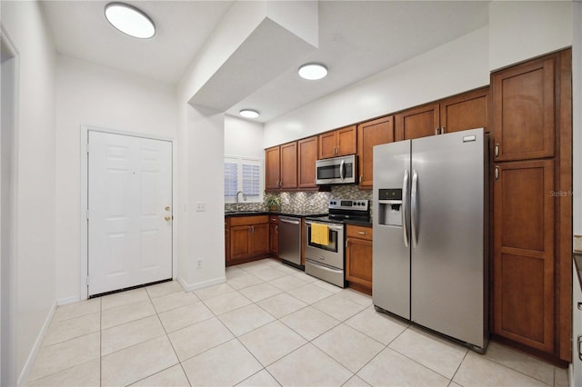 4260 Central Sarasota Pkwy Unit 213, Sarasota, FL 34238 - kitchen with appliances with stainless steel finishes, dark countertops, decorative backsplash, light tile patterned floors, and brown cabinetry