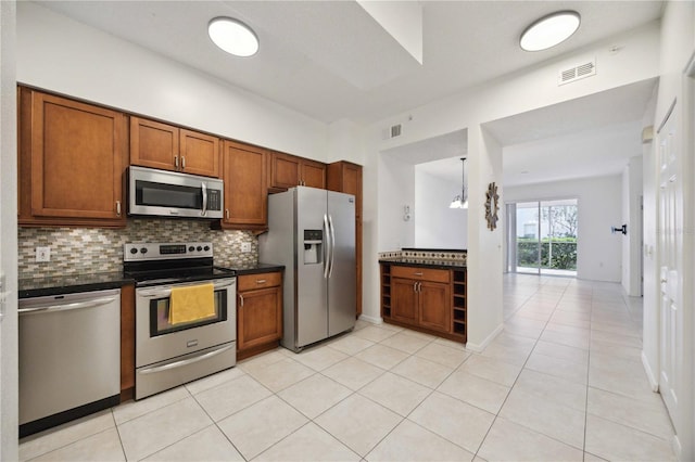 kitchen featuring appliances with stainless steel finishes, light tile patterned flooring, decorative backsplash, and an inviting chandelier