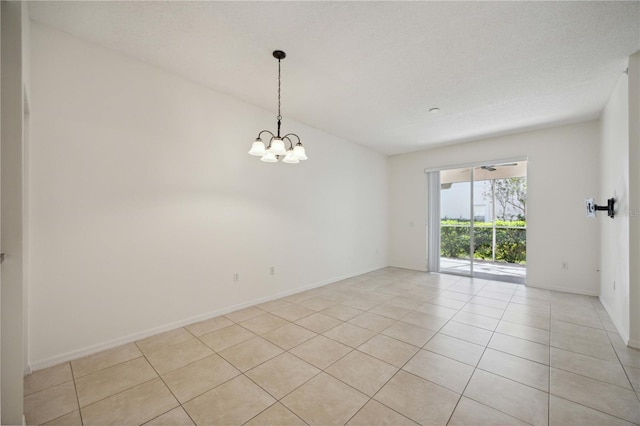 tiled spare room with a textured ceiling and a chandelier