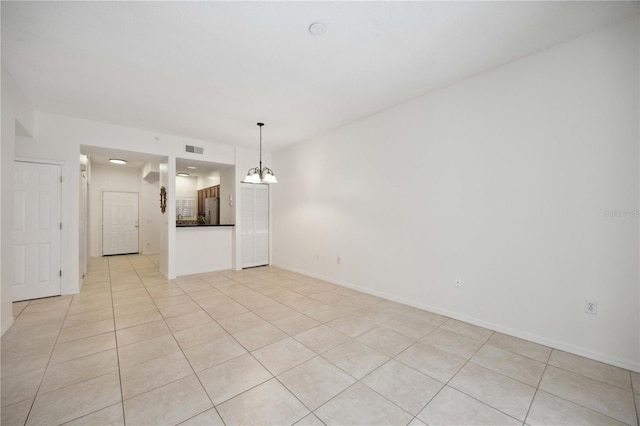 empty room with light tile patterned floors and an inviting chandelier