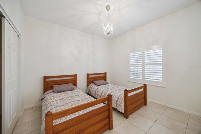 tiled bedroom with a notable chandelier and a closet