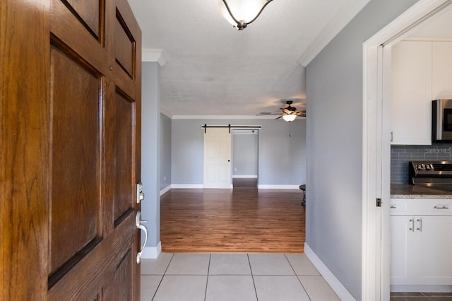 foyer featuring light hardwood / wood-style flooring, crown molding, a barn door, a textured ceiling, and ceiling fan