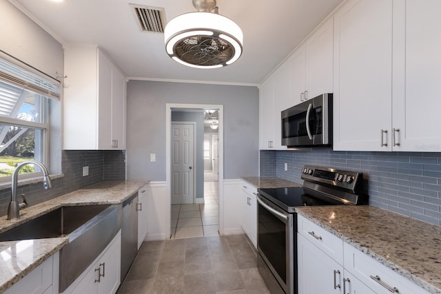 kitchen featuring light stone countertops, decorative backsplash, appliances with stainless steel finishes, and white cabinets