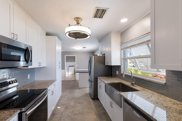 kitchen featuring light stone counters, backsplash, appliances with stainless steel finishes, white cabinetry, and sink