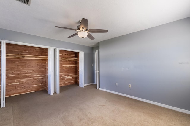 unfurnished bedroom with ceiling fan, wood walls, and carpet flooring