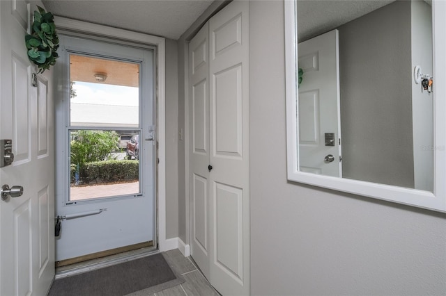 doorway to outside with a textured ceiling