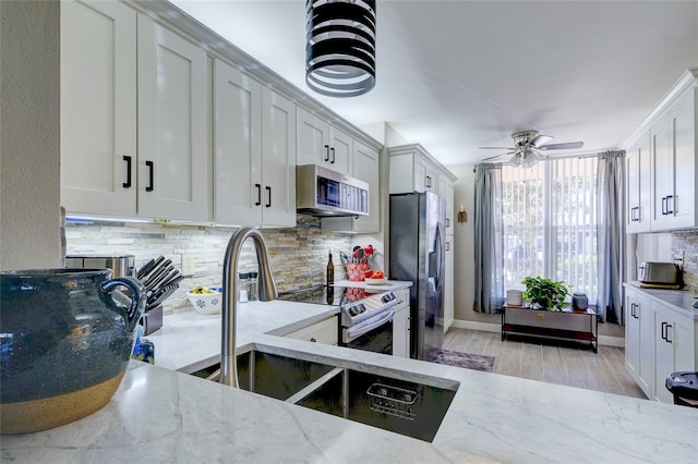 kitchen featuring backsplash, white cabinetry, light stone countertops, light hardwood / wood-style floors, and stainless steel appliances