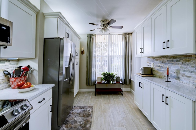 kitchen with light stone countertops, backsplash, appliances with stainless steel finishes, and white cabinets